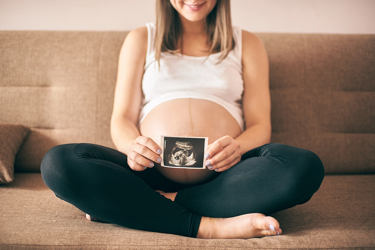 Image of a pregnant lady holding a scanned picture of her baby.