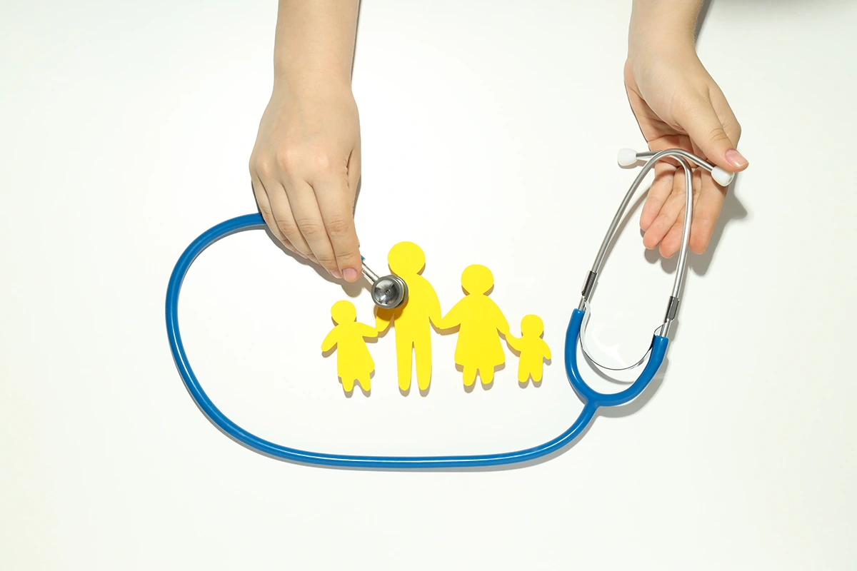 An image of a person holding a stethoscope, checking a family that is represented by paper cutout.